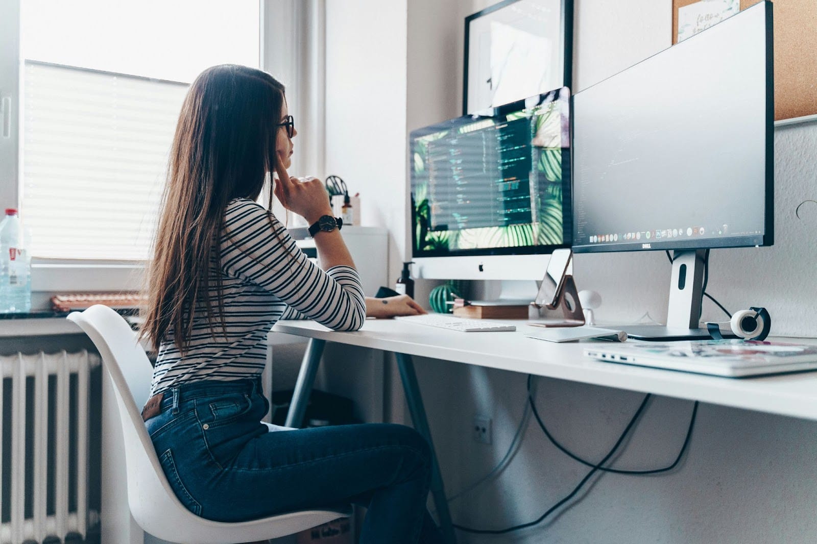 Young woman locked in on her desktop computer, fully immersed in work inside a cozy, dimly lit room.