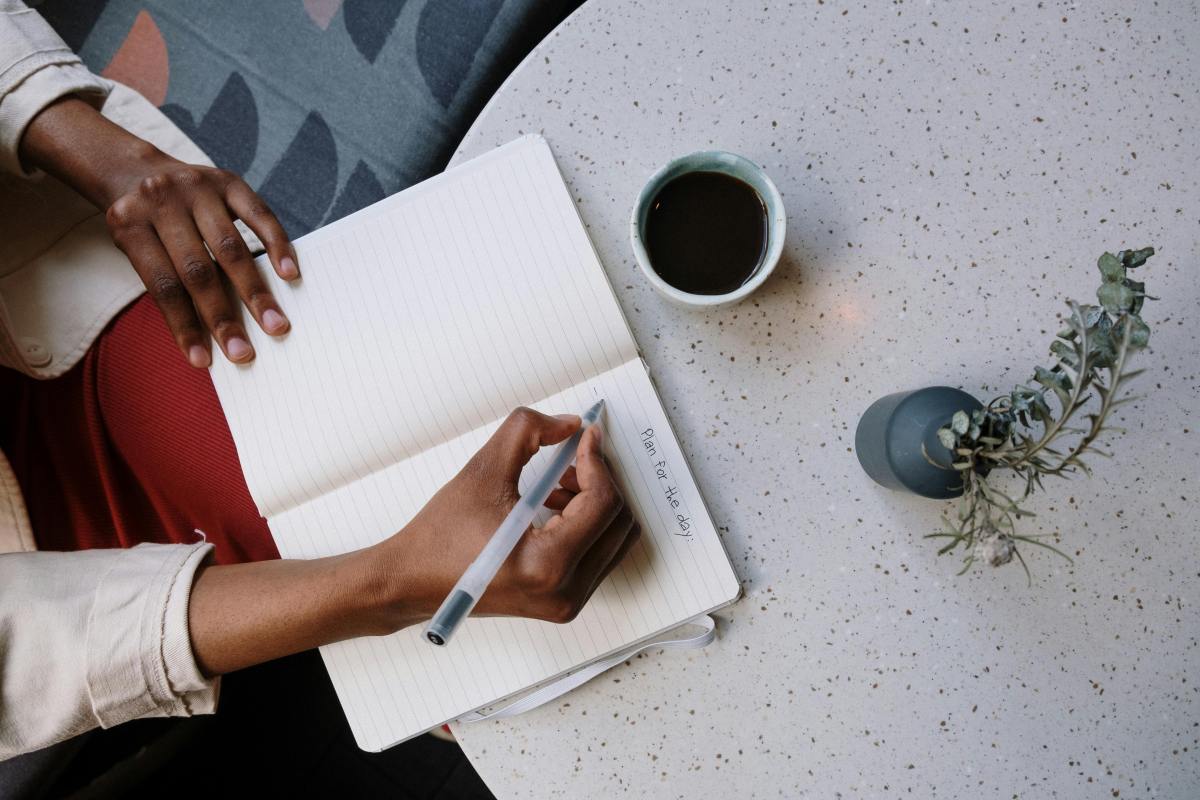 Person writing in a book – planning SMART goal setting strategies.
