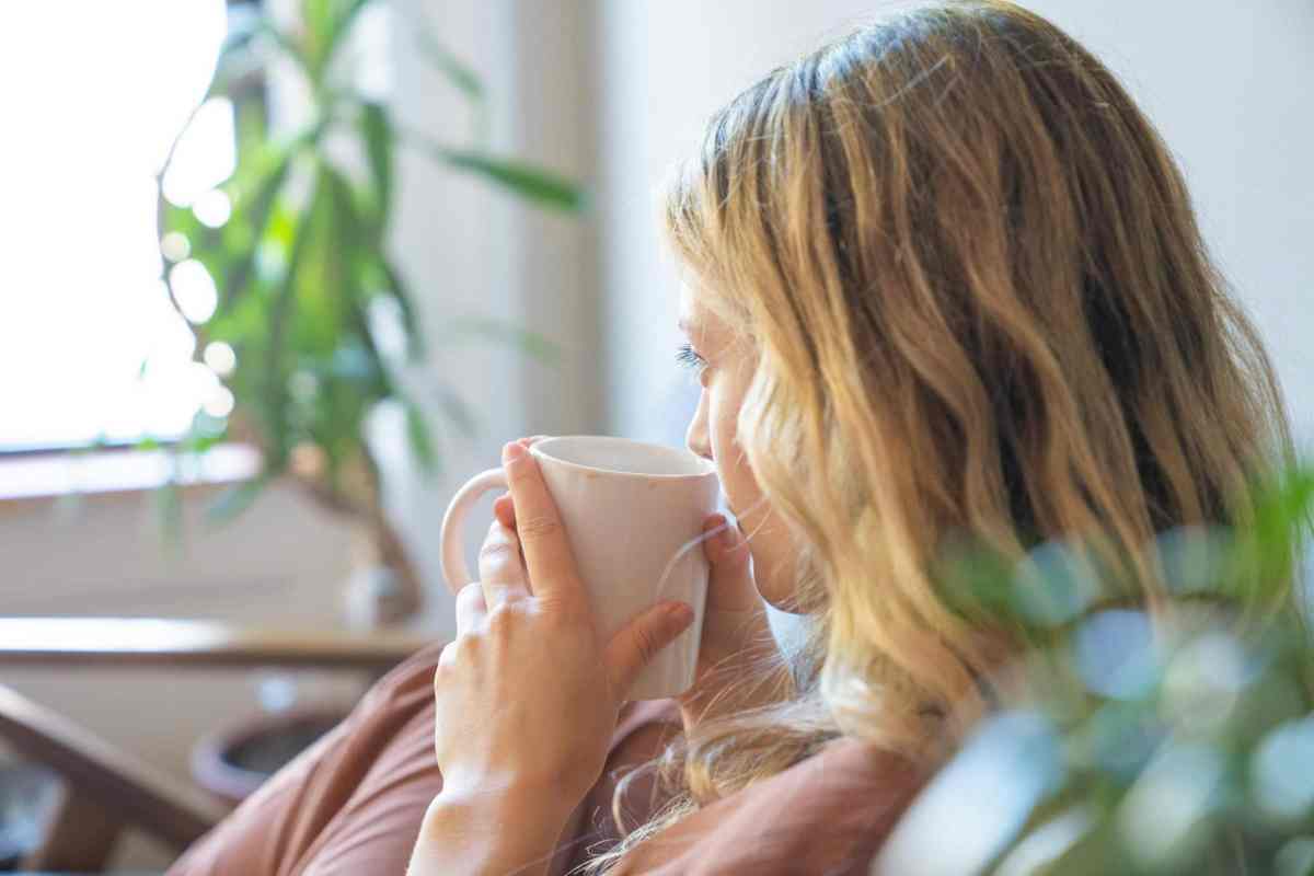 Woman drinking morning coffee mindfully, practicing timing strategies for a cortisol detox.