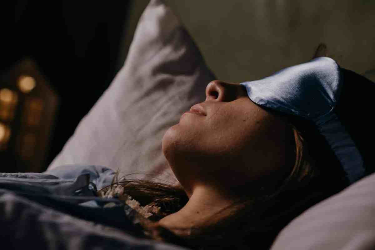 Woman asleep wearing an eye mask, symbolizing restful sleep avoiding insomnia.