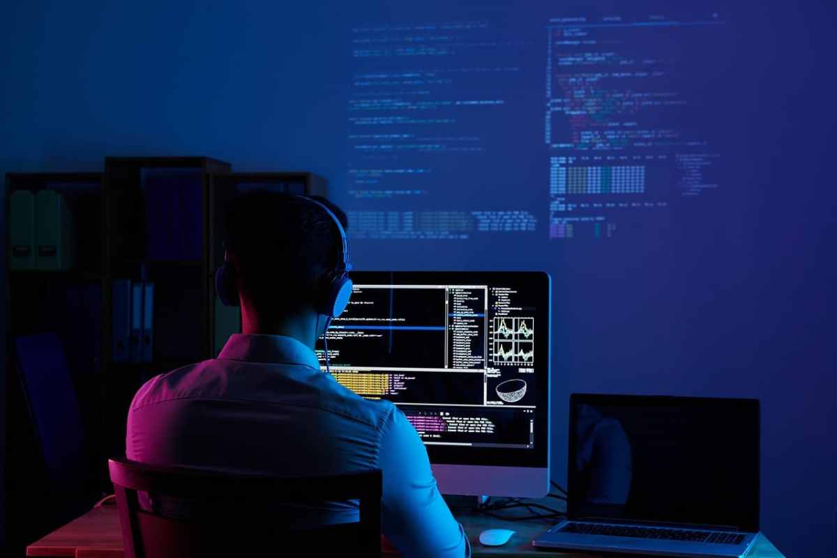 A focused software developer working at a multi-monitor setup with code on screens, symbolizing deep work and vibe coding.